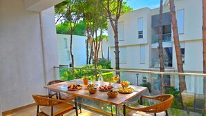 A balcony with a table set for breakfast, wicker chairs, and a view of buildings and trees. - SanPietro Holiday Homes 287 (Gjiri Lalzit)
