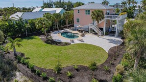 A residential property with a swimming pool, a covered patio, and a well-maintained lawn. - Boca Grande Pool Home 343 - 4 bedroom / 4 Bath - Steps to Beach! (Boca Grande)