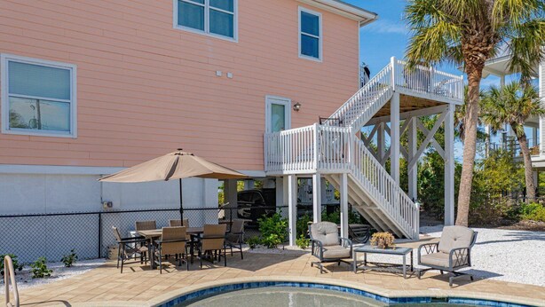 A pool area with a wooden deck, outdoor furniture, and a staircase leading to a balcony. - Boca Grande Pool Home 343 - 4 bedroom / 4 Bath - Steps to Beach! (Boca Grande)