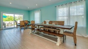 A dining area with a long wooden table, wicker chairs, and a bench. - Boca Grande Pool Home 343 - 4 bedroom / 4 Bath - Steps to Beach! (Boca Grande)