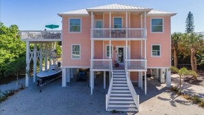 A two-story building with a balcony, a covered porch, and a staircase leading to the entrance. - Boca Grande Pool Home 343 - 4 bedroom / 4 Bath - Steps to Beach! (Boca Grande)