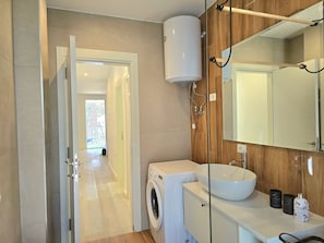 A modern bathroom with a washing machine, a sink, and a large mirror. - SanPietro Holiday Homes 294 (Gjiri Lalzit)