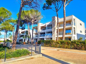 A multi-story hotel with balconies, surrounded by trees and a paved walkway. - SanPietro Holiday Homes 294 (Gjiri Lalzit)