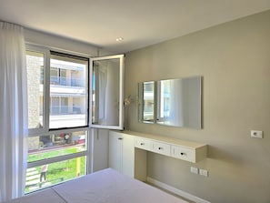 A bedroom with a bed, a large window, a mirror, and a built-in cabinet.