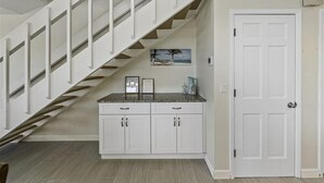 A staircase with white railings leading to a landing with a kitchen counter and cabinets.