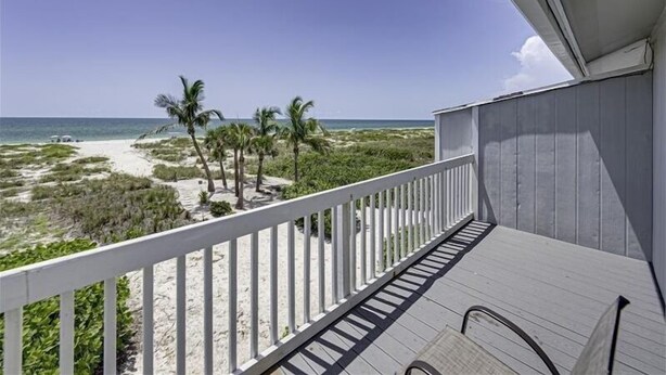 A balcony with a view of the beach and ocean.