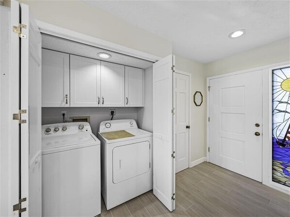 A laundry room with a washing machine, dryer, and cabinets.