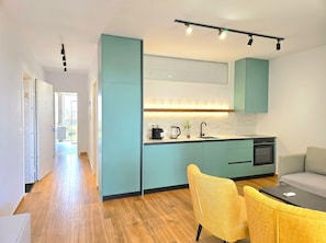 Une cuisine moderne avec des armoires de couleur turquoise, un poêle noir et un coin repas avec des chaises jaunes.