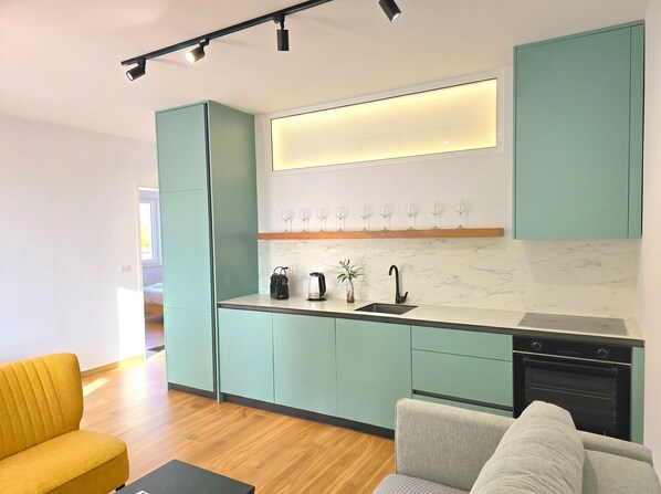 A modern kitchen with teal cabinets, a marble backsplash, and a built-in oven. - SanPietro Holiday Homes 296 (Gjiri Lalzit)