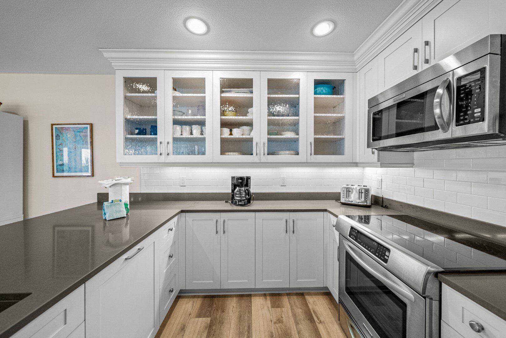 A modern kitchen with white cabinets, a stainless steel microwave, a coffee maker, and a toaster.