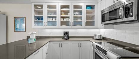 A modern kitchen with white cabinets, a stainless steel microwave, a coffee maker, and a toaster.
