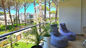 A balcony with a view of modern buildings, a potted plant, and two bean bags. - Wide Beach Apartments 289 (Gjiri Lalzit)