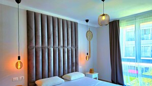 A modern bedroom with a large bed, two bedside tables, and a large window with curtains. - Wide Beach Apartments 289 (Gjiri Lalzit)