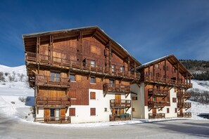 A large wooden chalet with multiple balconies and a ski slope in the background.