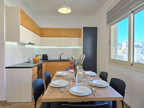 A modern kitchen with a dining area, wooden cabinets, and a large window.