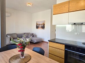 Une cuisine moderne avec des meubles en bois, un four encastré et un coin repas comprenant une table et des chaises.