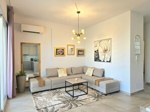 Un salon moderne avec un canapé d’angle, une table basse et un grand miroir.