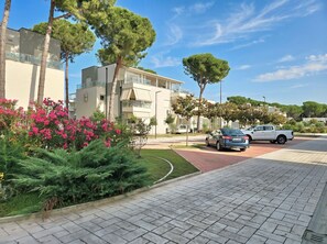 Un quartier résidentiel avec des immeubles modernes, une promenade dallée et des voitures garées.