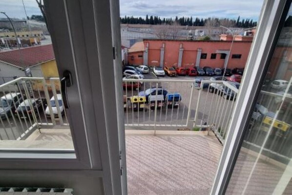 A view from a balcony overlooking a parking lot with several cars and a building in the background. - L'Impero dei fiori Vacation Home in Rome (Roma)