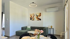 Un'elegante zona pranzo con un divano grigio, un'opera d'arte astratta appesa alla parete e un tavolo imbandito con piatti, bicchieri e un vaso di fiori.