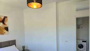 Una camera d'albergo con un letto, un quadro, una lavatrice e una luce a soffitto.