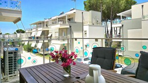 Un balcon avec une table, un vase de fleurs et une bouteille d’eau.