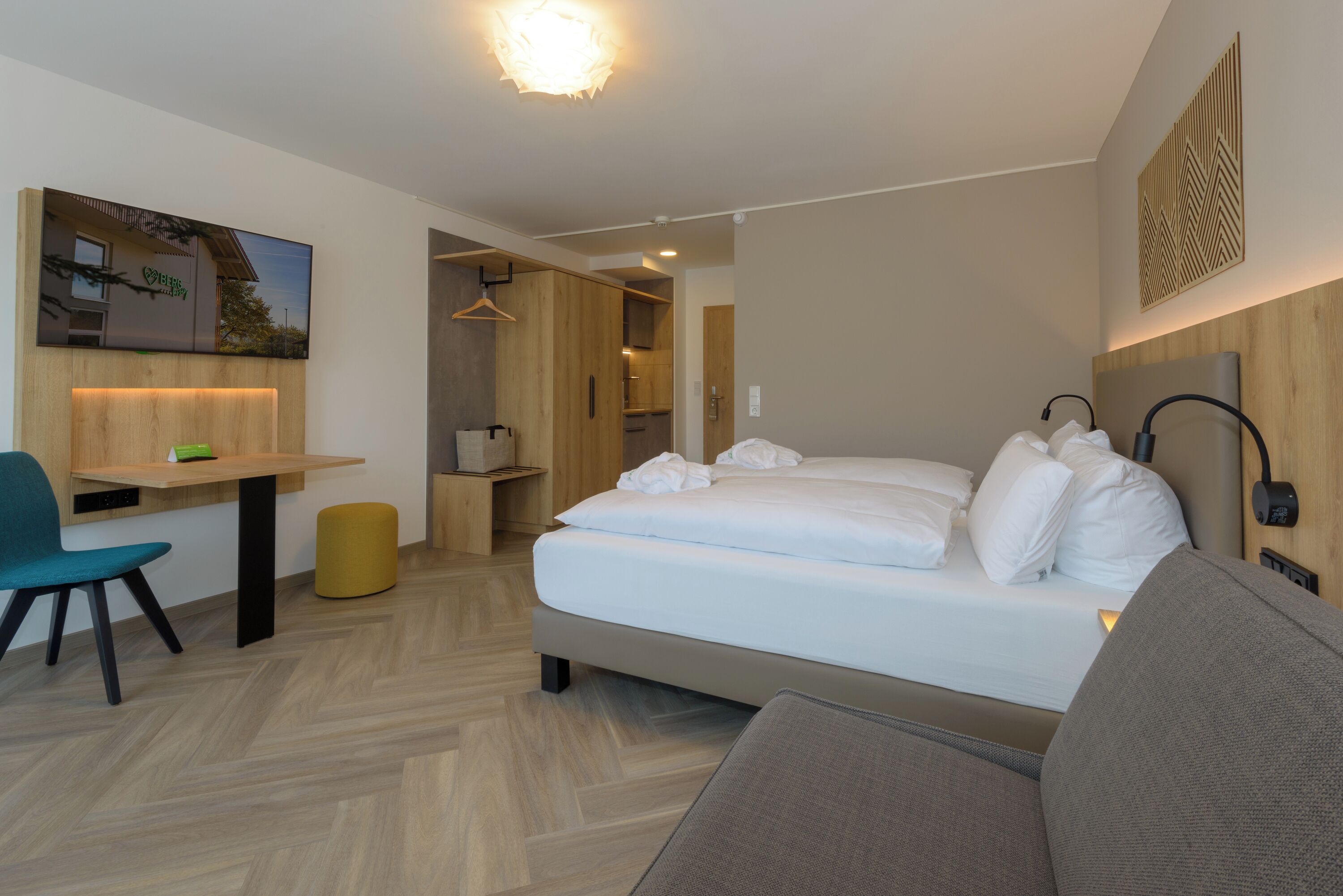 Ett modernt hotellrum med en säng, ett skrivbord, en stol och en soffa.