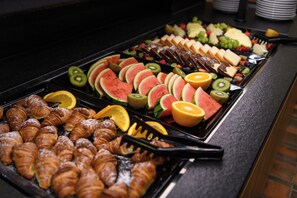 Ein reichhaltiges Buffet mit verschiedenen Speisen, darunter Obst, Gebäck und Käse.