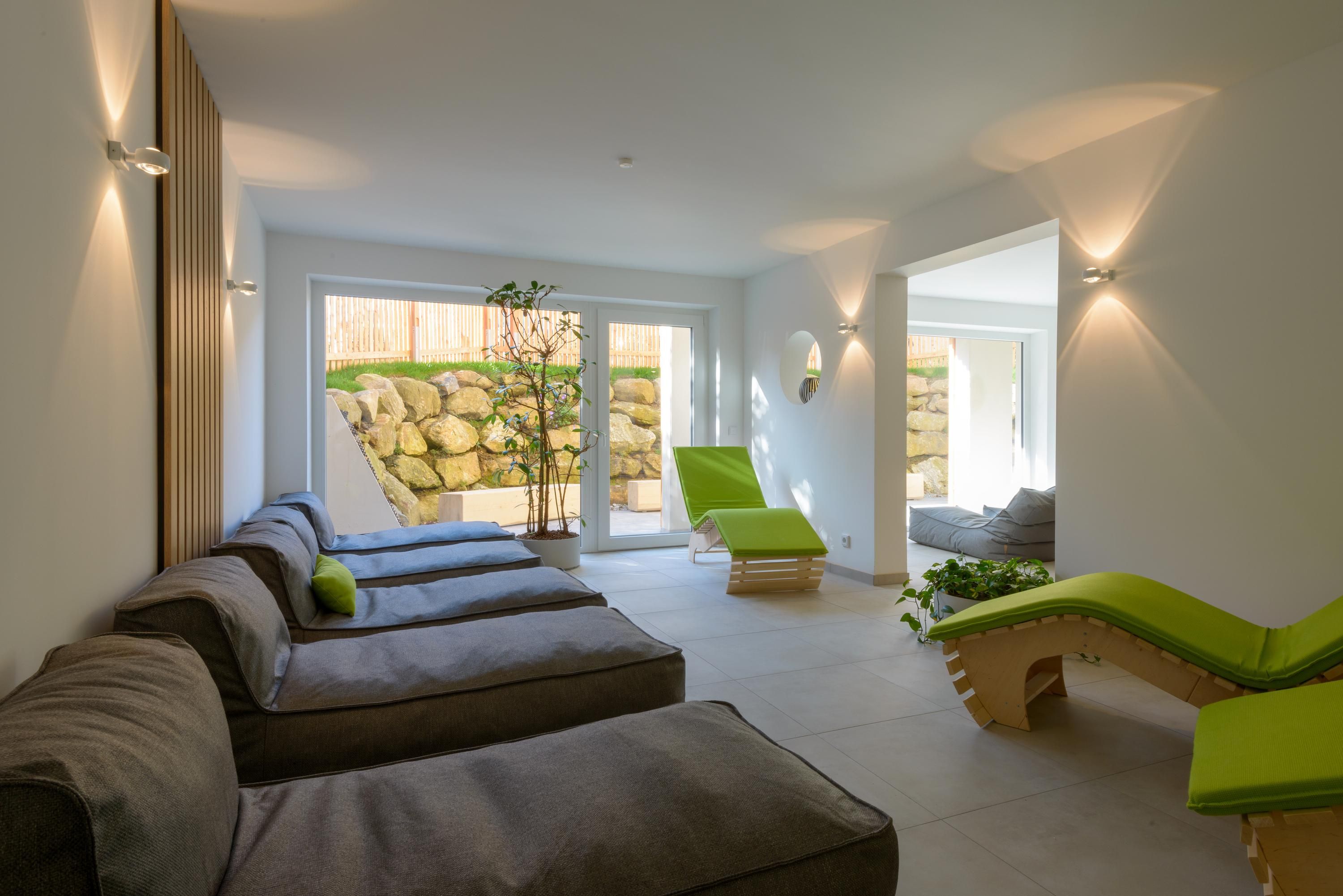 A spa room with a row of massage tables, a green chair, and a stone wall.