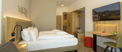 Una habitación de hotel moderna con una cama grande, un escritorio, una silla y un cuadro en la pared.