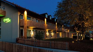 Un hôtel au design moderne, doté d’une clôture en bois, d’une entrée bien éclairée et d’une enseigne.