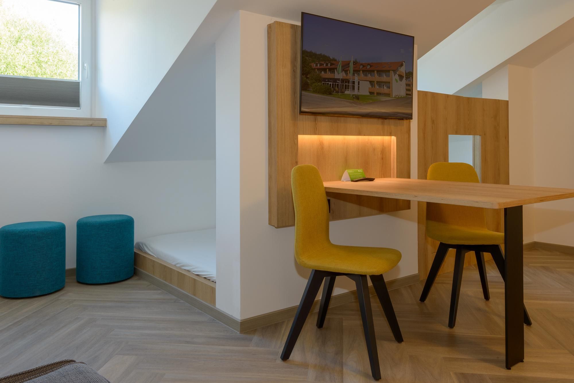 Ein modernes Zimmer mit einem Holzesstisch, zwei gelben Stühlen und einem blauen Sofa.