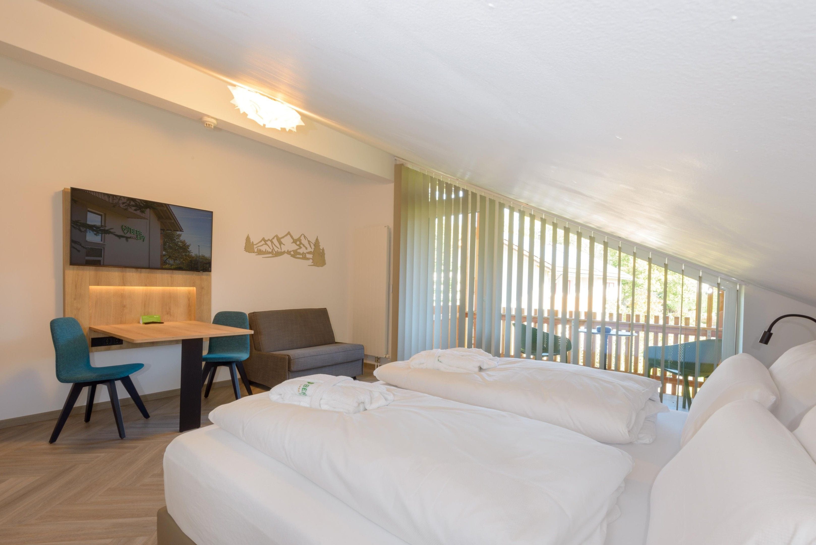 Een moderne hotelkamer met een bed, een bureau, een stoel en een bank.