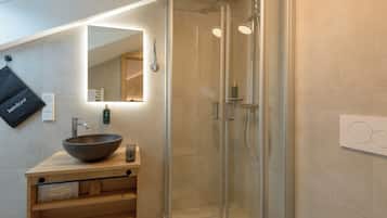 A modern bathroom with a large mirror, a vessel sink, and a glass-enclosed shower.