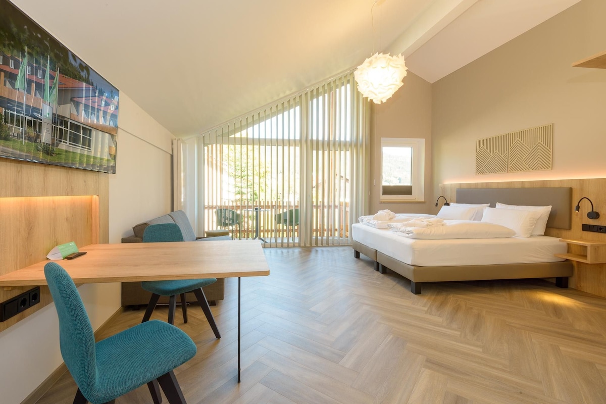 A modern hotel room with a bed, a desk, and a chair.