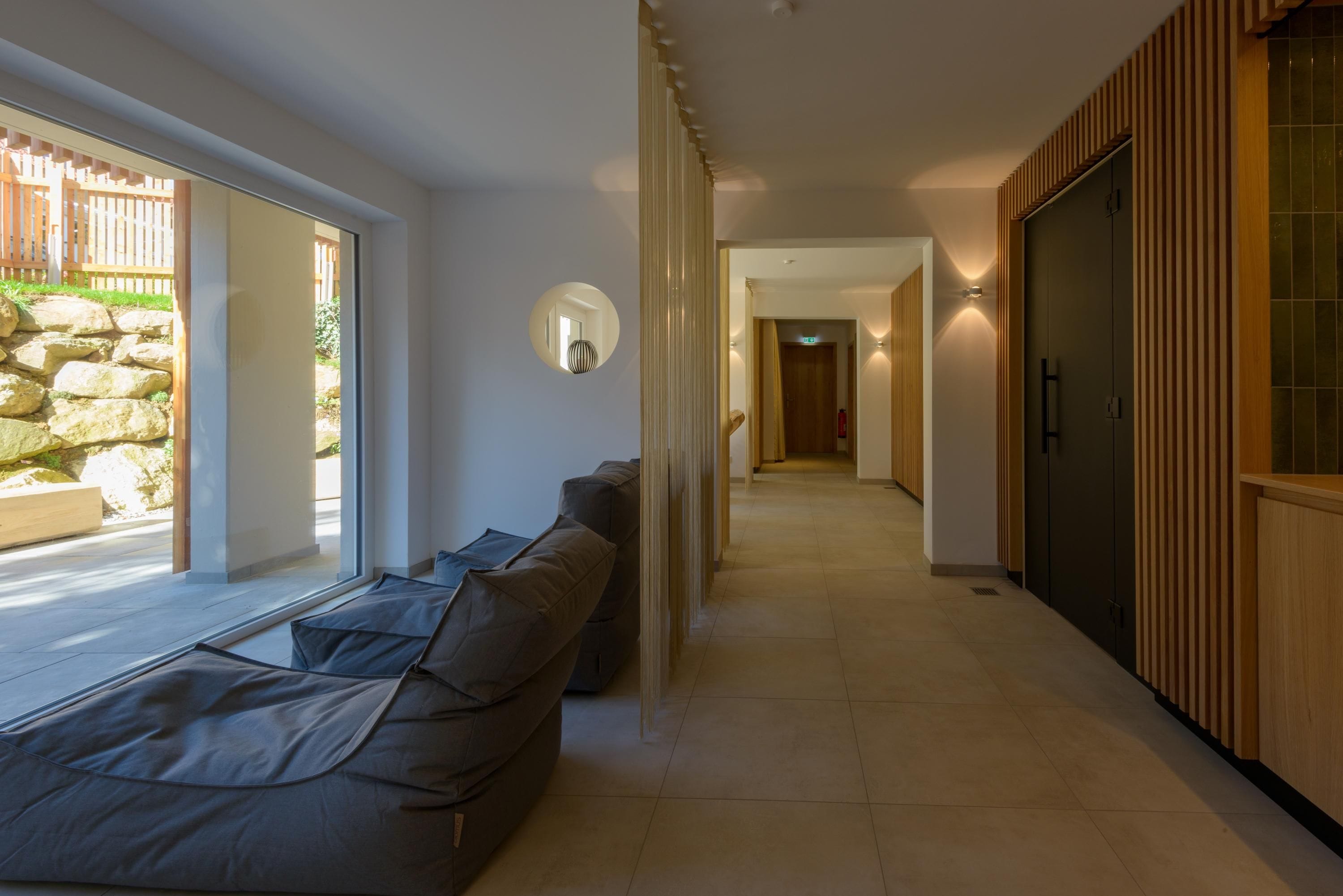 A modern interior with a long hallway, a sofa, and a stone wall.