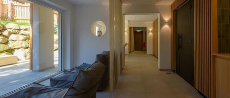 A modern interior with a long hallway, a sofa, and a stone wall.