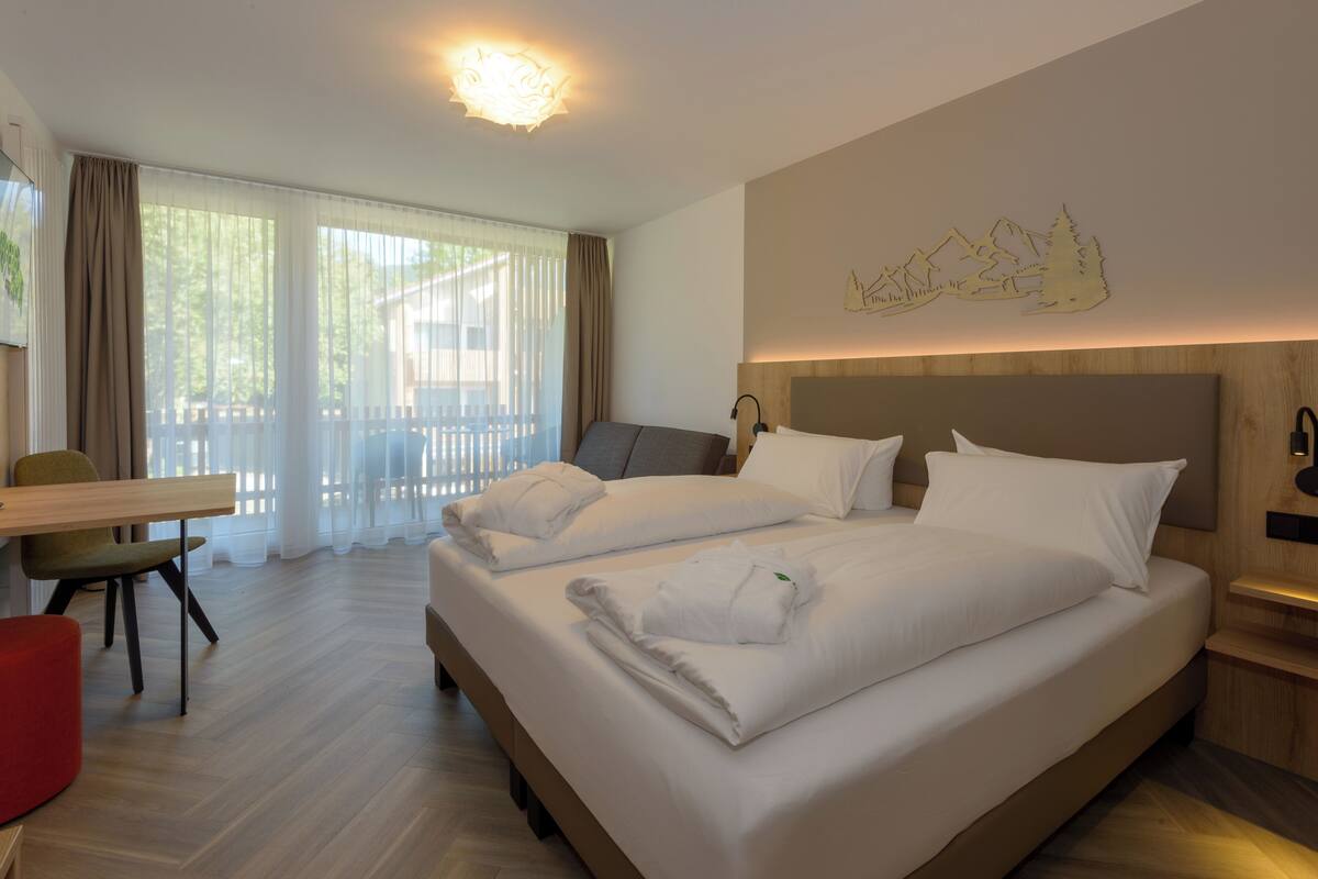 Ein Hotelzimmer mit zwei Betten, einem Schreibtisch und einem Sessel.