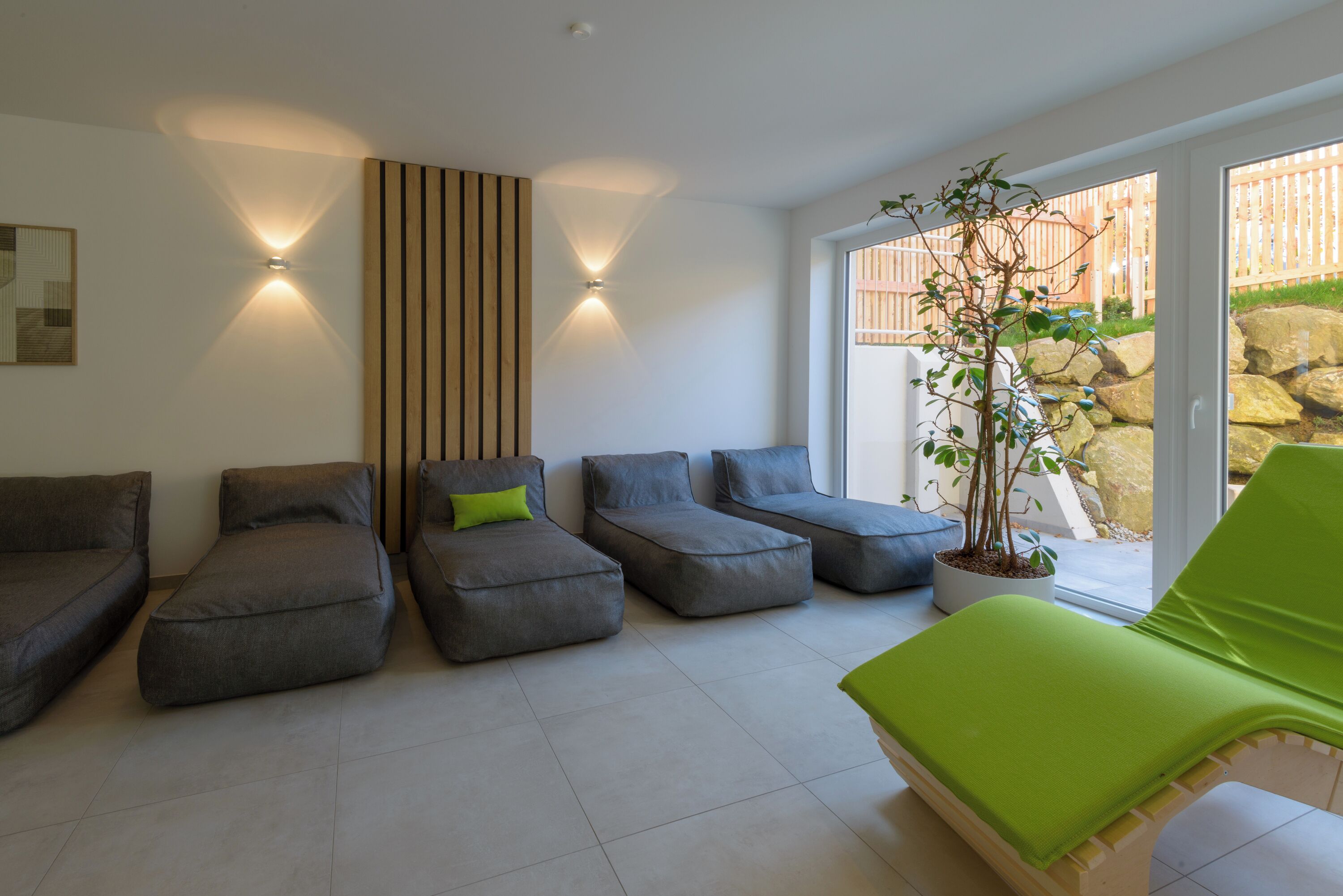 Un salon moderne avec des canapés gris, un fauteuil vert et une plante en pot.