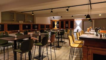 Un comedor moderno con varias mesas y sillas, armarios de madera e iluminación colgante.