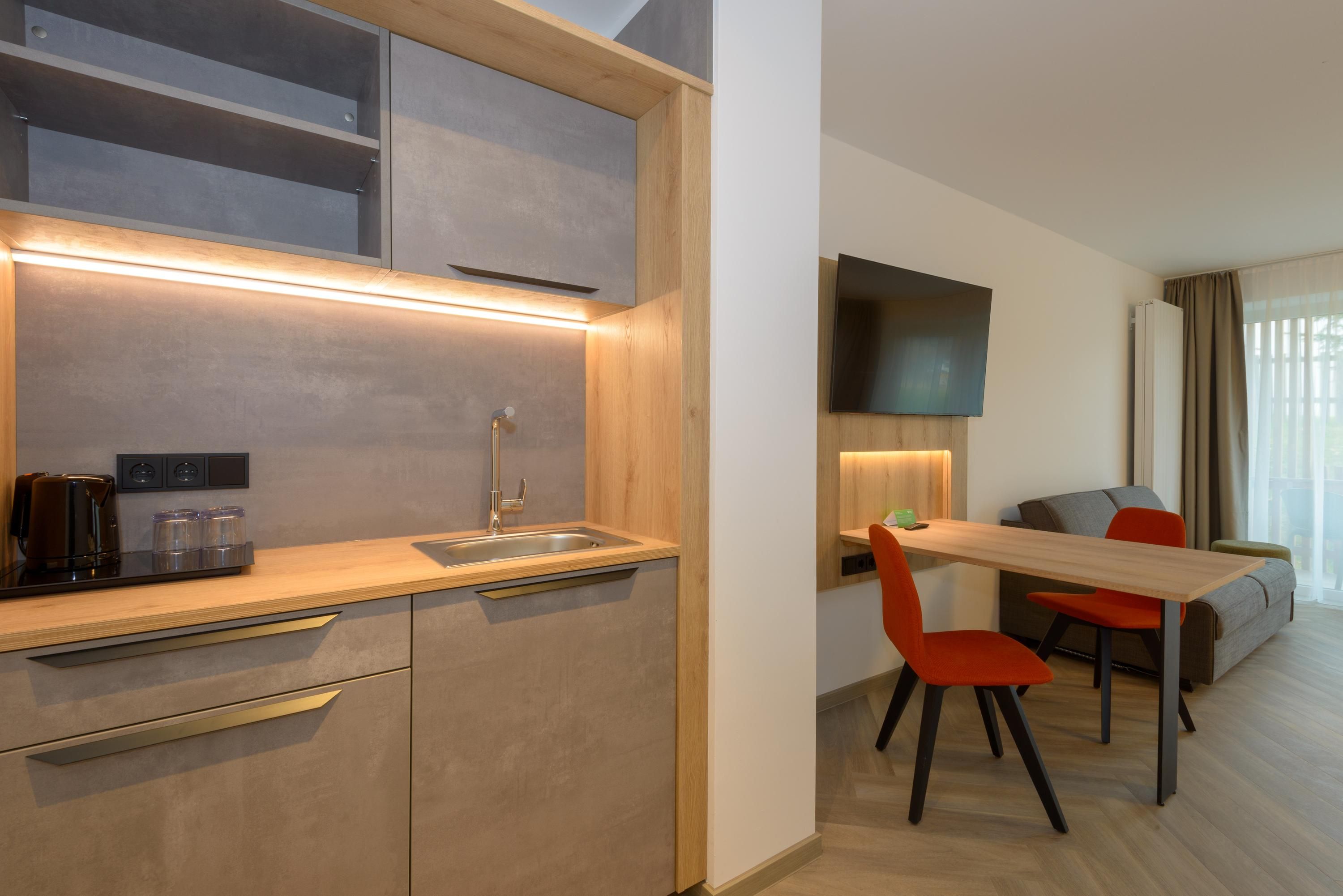 A modern kitchenette with a built-in oven, a sink, and a coffee maker.