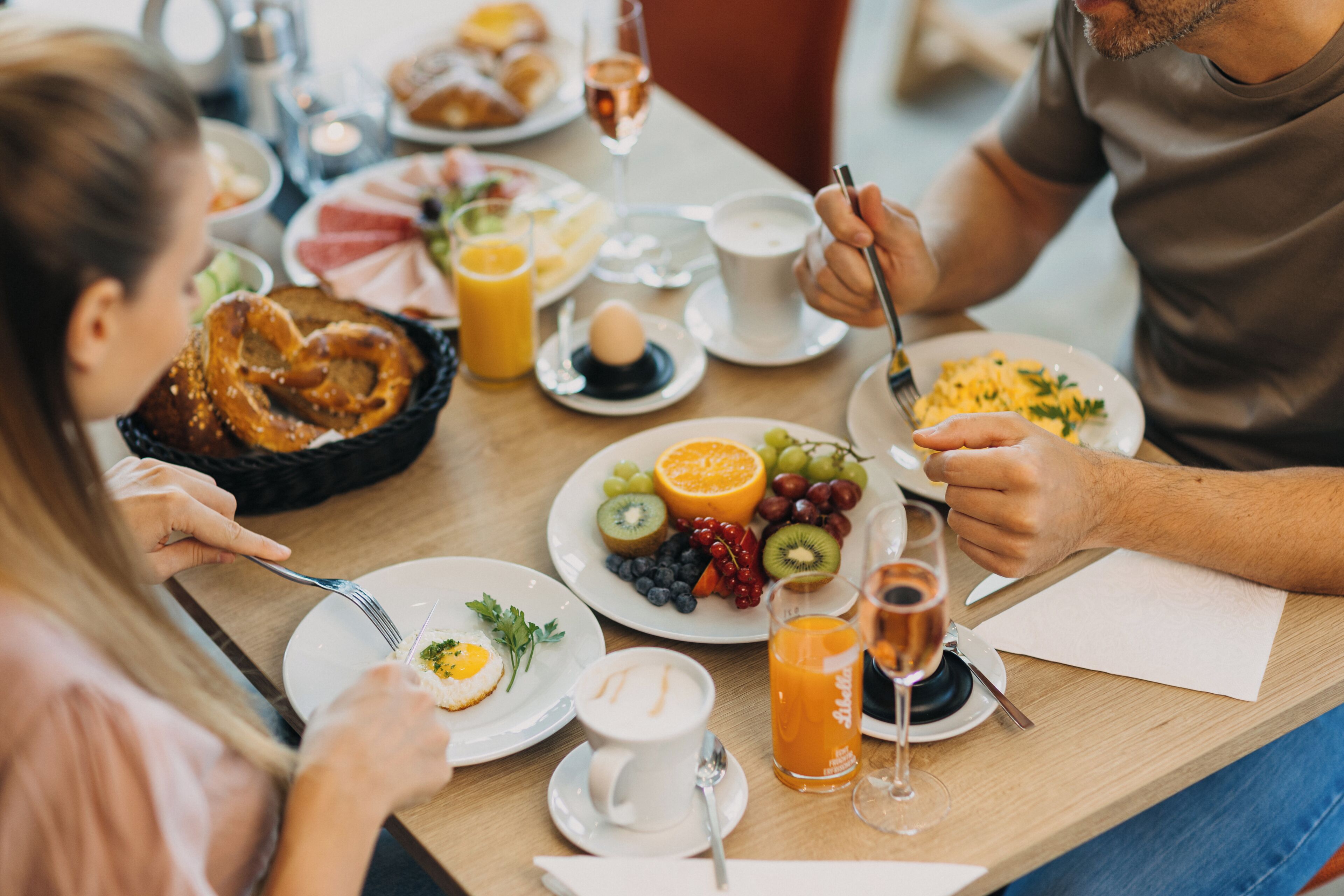 Une table mise pour le petit-déjeuner, avec des assiettes remplies de nourriture, une tasse de café et un verre de jus d’orange.