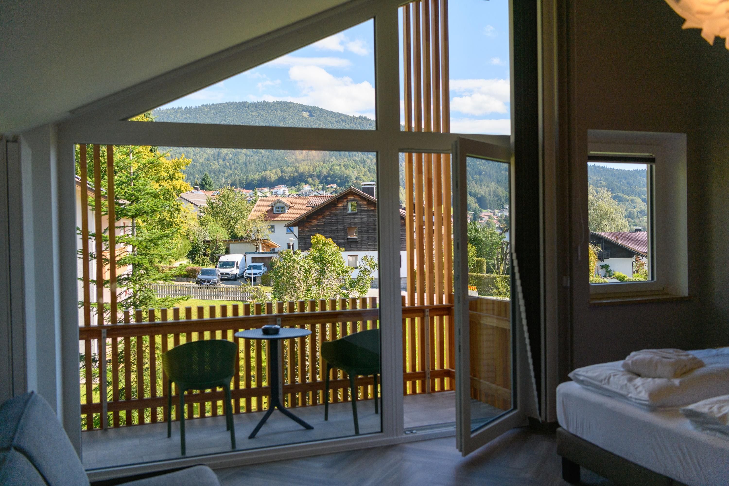 A room with a balcony, a bed, and a table with chairs.
