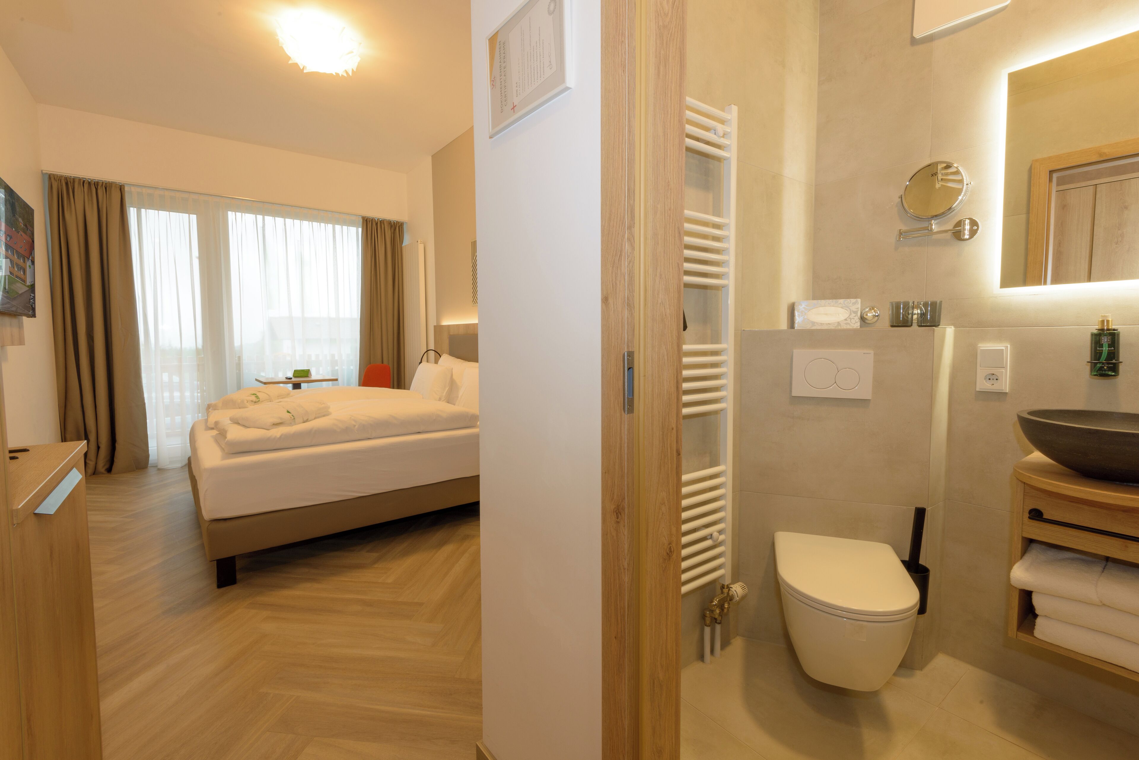 A hotel room with a bed, a bathroom with a toilet, and a sink.