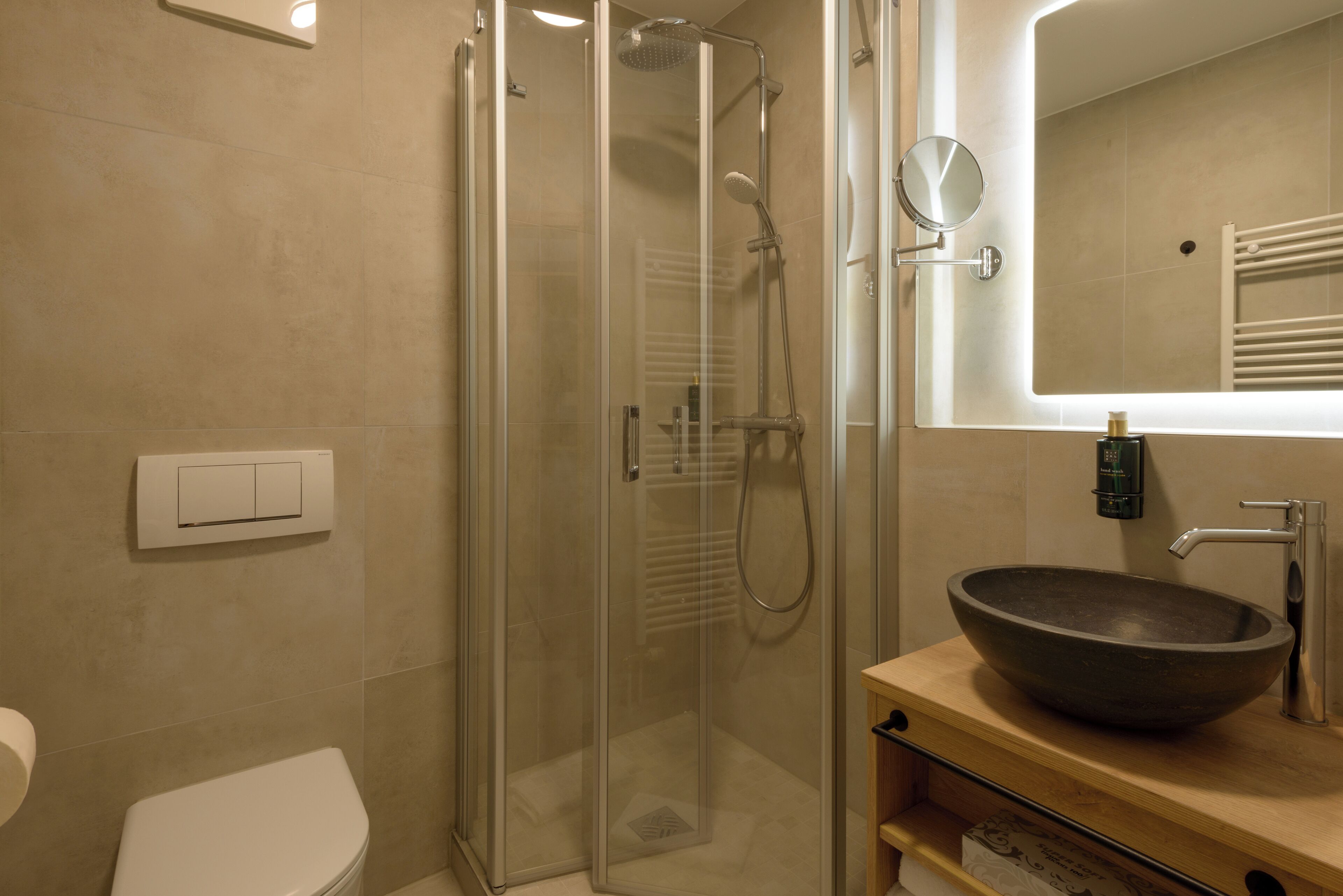 Un baño moderno con ducha envuelta en vidrio, un lavabo de diseño y un espejo sobre el lavabo.