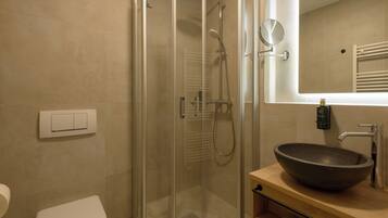 Un baño moderno con ducha envuelta en vidrio, un lavabo de diseño y un espejo sobre el lavabo.