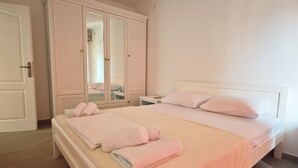 Quarto com uma cama de casal, guarda-roupa e espelho.