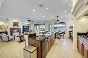Una cocina amplia con una isla central, comedor y chimenea.