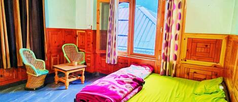 A room with a bed, a chair, a table, and a ceiling fan.