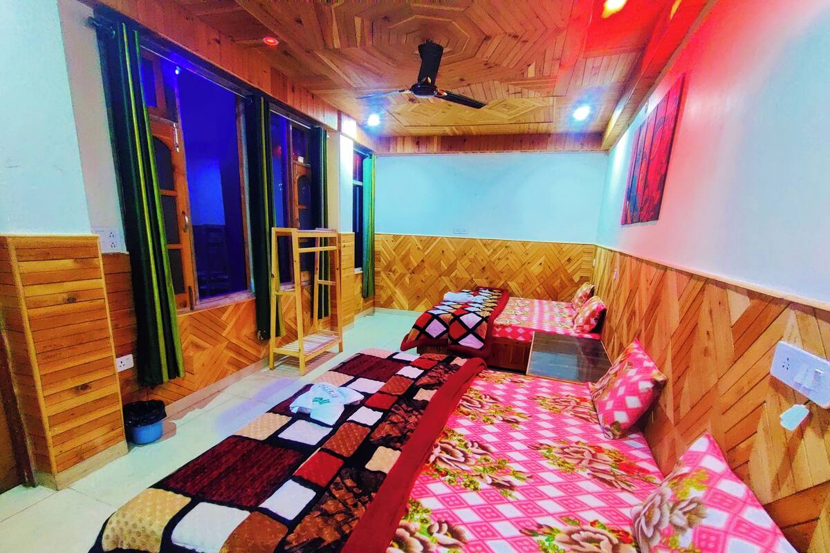 A room with two beds, a wooden ceiling, and a window with curtains.